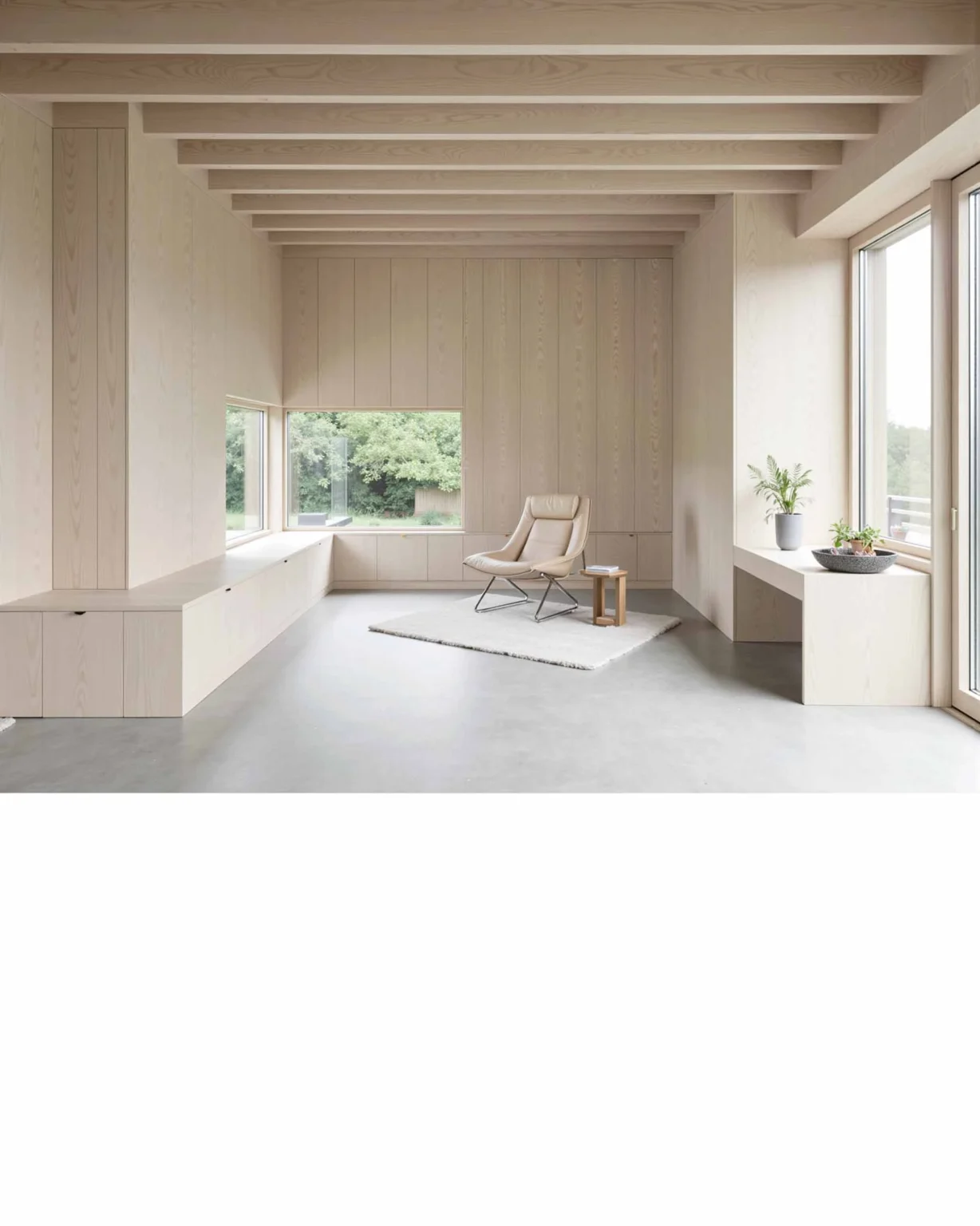 Salon rural moderne et contemporain en bois clair avec assises intégrées sous les fenêtres et vue sur jardin, conception architecturale par Arthur Montessuit, Architecte en Haute-Savoie.